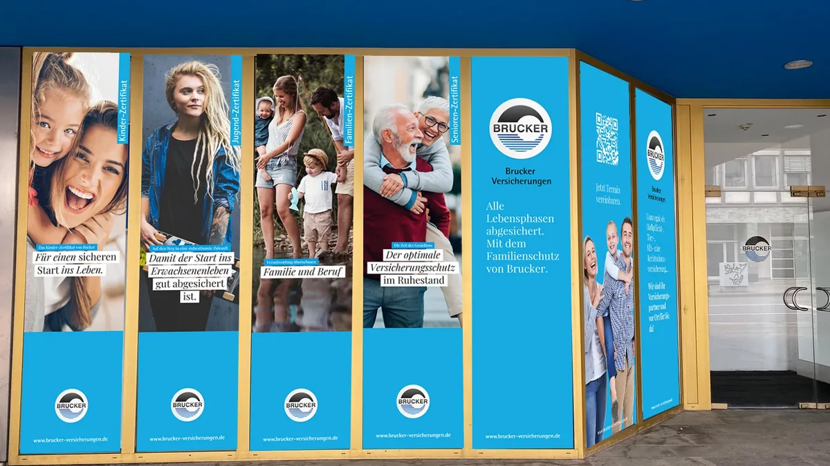 Schaufenster-Layout am Stammsitz: hohe Fensterfolien mit Freistellern und der Brucker-Plakette auf Signalblau