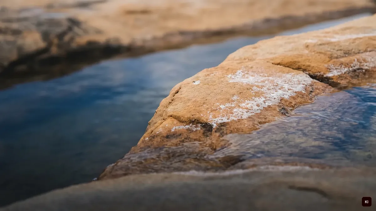 Wasser, das über Sandstein fließt, Salzspuren im Vordergrund, KI-Bild