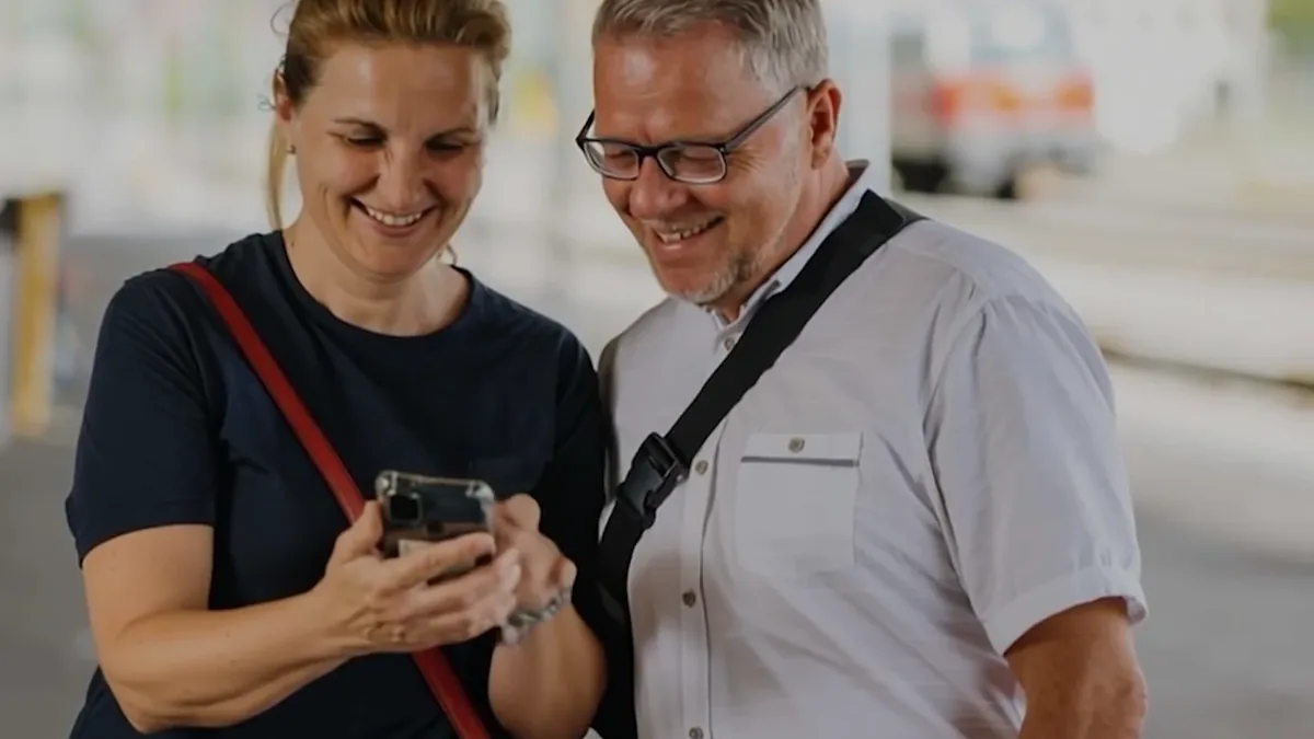 Filmstill: Paar mit Smartphone am Bahnsteig
