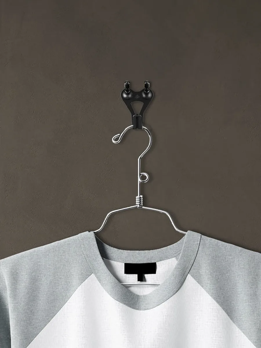 Grauweißes Shirt auf einem Kleiderbügel an einem schwarzen FLOREAT-Haken vor brauner Wand