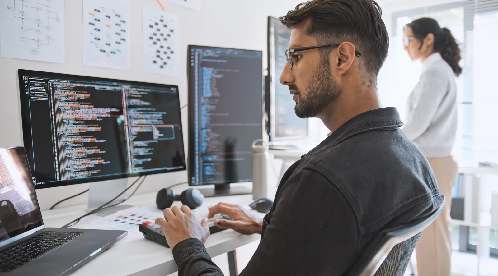 Entwickler arbeitet am Code auf zwei Bildschirmen